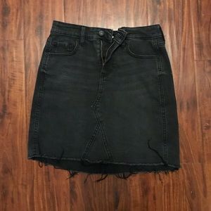 Black denim skirt with distressed bottom hem.